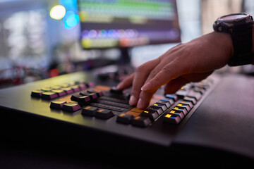 Closeup image of a hand mixing sounds on a control board, showcasing an audio technicians work