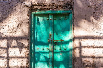 Sonnendurchflutete Gasse mit grüner Metalltür – Nizwa, Oman