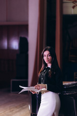 Elegant Young Woman Holding Sheet Music by a Grand Piano