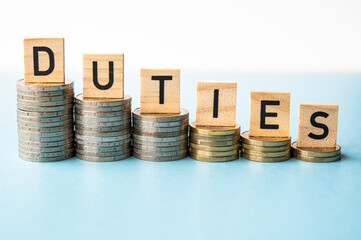 Stacks of coins of decreasing height and wooden tiles that spell out the word duties. Consequences of new duties.