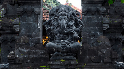 An old hindu stone statue of Ganesha covered with moss, standing on the str..