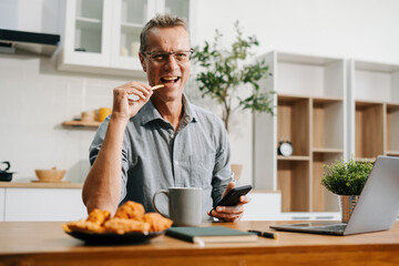 Happy mature male enjoying work at home office.