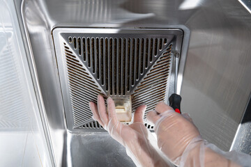 unscrew the screws of the filter hood from a kitchen ventilator