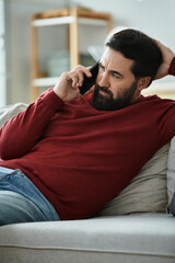 Handsome elderly man enjoys a casual conversation on the phone in a cozy living room setting