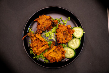 Chef preparing delicious indian food with fried shrimps, lemon and cucumber slices