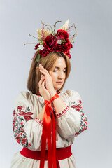 Young woman in traditional attire gracefully poses with decorative crown and ribbons