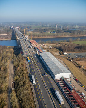 Highway bridge construction over Kiel Kanal by Rade. Rade High Bridge under construction over Nord-Ostsee-Kanal, showing traffic on multiple lanes, temporary structures, cranes, a construction site.