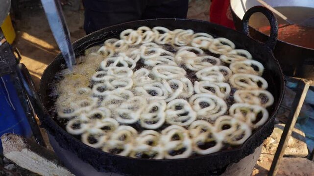Jalebi is being fried in a large pan	

