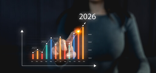 A person interacts with a digital graph displaying upward trends, forecasting data for the year...