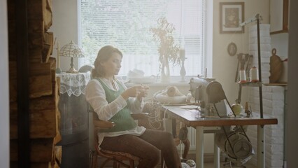 A woman sewing in a sunlit, cozy workspace beautifully decorated with artistic elements