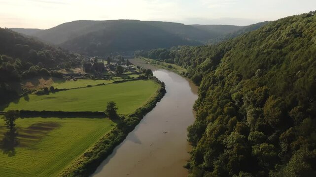 Aerial drone footage of the River Wye and Tintern Abbey on a sunny summer day, capturing scenic landscapes and historic architecture.
