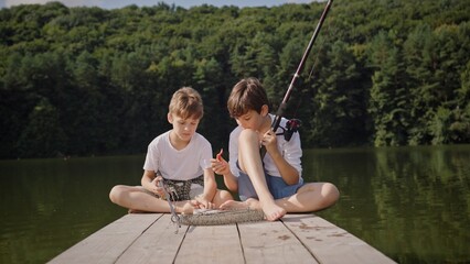 Two Kids Engaging in a Fun Fishing Activity at a Serene Lakeside Dock, Enjoying Nature