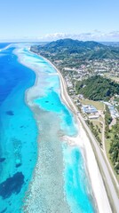 Fototapeta premium Aerial view of tropical island's turquoise coast showing ocean, road, & hills. Use for tourism ads