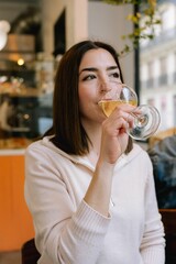 Young woman enjoying a glass of wine in a cozy cafe.