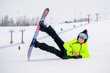 Young snowboarder posing on snowy slope dressed in stylish winter gear.