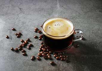 Hot coffee glass cup  and coffee beans on gray background, espresso coffee in a transparent cup with crema