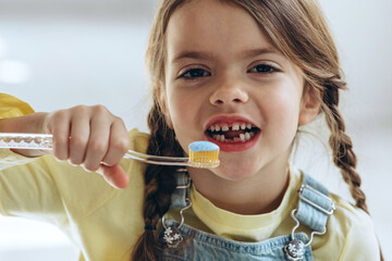 Portrait, smile and girl brushing teeth in bathroom for dental, health or oral care in her home. Happy and beautiful child in home with toothbrush brushing teeth.