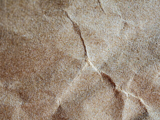 Brown background with wrinkled paper texture. The background has a natural brown color and a wrinkled and textured appearance. light brown background