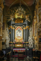 The interior of the Basilica of St. Michael the Archangel on Skałka in Kraków, Poland, showcases magnificent Baroque architecture, adorned with intricate gold detailing, frescoes, and religious iconog