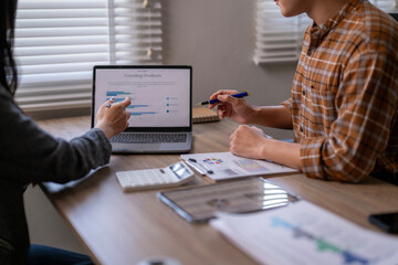 Two people are sitting at a table with a laptop and a projector