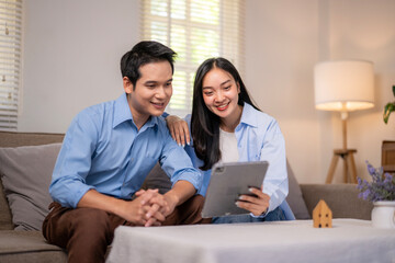 A man and woman are sitting on a couch looking at a tablet
