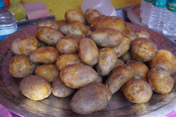 A pile of boiled potatoes with its peel on a metal tray in a store