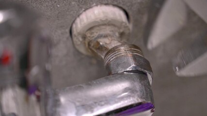 Professional maintenance worker tightening loose faucet connections using adjustable wrench, performing precision plumbing repairs in residential bathroom or kitchen setting