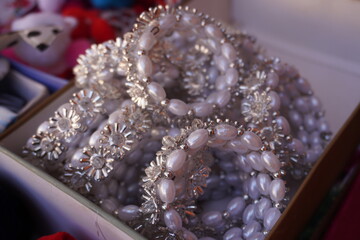 Several strands of pearl and crystal jewelry piled in a box which  includes strands of pearls and strands with crystal flower-shaped embellishments