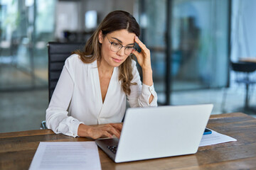 Fatigued worried mature business woman wearing glasses having headache at work. Tired busy 40s...