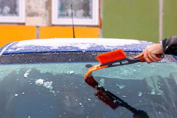 A person is cleaning the cars windshield with a brush