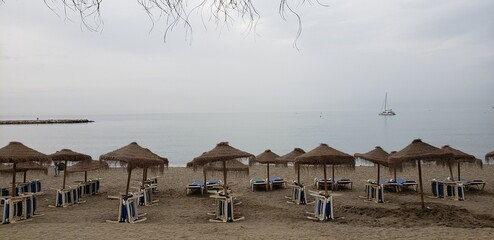 Tranquil Beachfront: A Line of Straw Umbrellas on a Calm Sea Day.