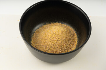 Ground fenugreek seeds in black bowl, milled dry trigonella powder, spicy methi dana pounded