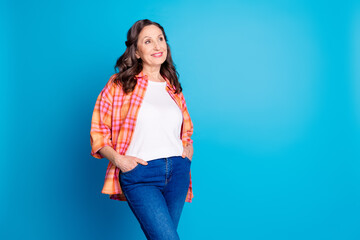 Charming senior woman smiling in casual clothing against a bright blue studio background, exuding confidence and style