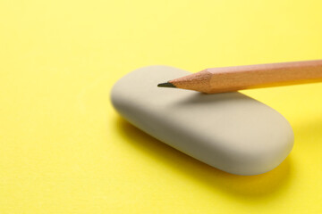 Eraser and pencil on yellow background, closeup