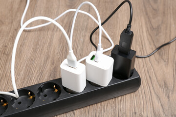 USB adapters with charge cables in power strip on floor, closeup