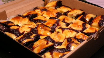 Yellow and black brownie pieces in a tempting paper box with crunchy almond topping on top. Sweet and delicious snacks are perfect for boosting spirits and happiness throughout the day.