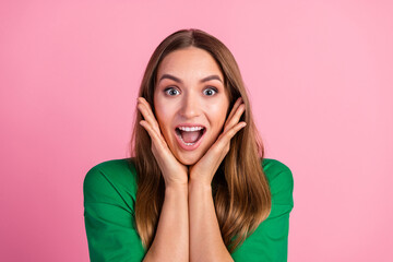 Excited Young Woman in Green Shirt Showing Expression of Joy Against Pink Background