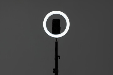 Ring lamp with smartphone on grey background