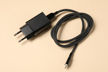 USB power adapter with charge cable on beige background, above view