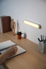 Obraz premium Woman working at desk with LED lamp on wall, closeup