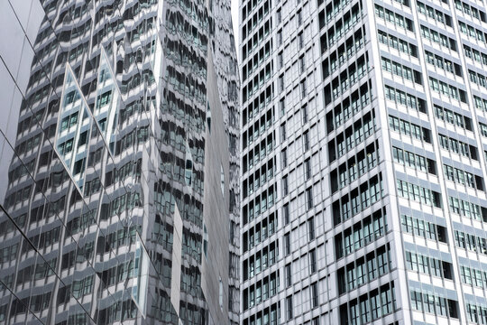 Modern glass skyscrapers reflecting the urban skyline, creating a geometric pattern of transparency and light.