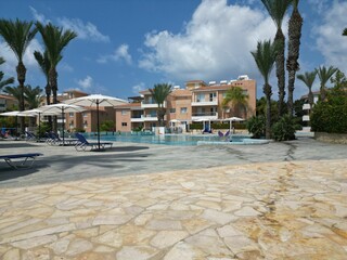 Luxurious resort poolside with palm trees and loungers.