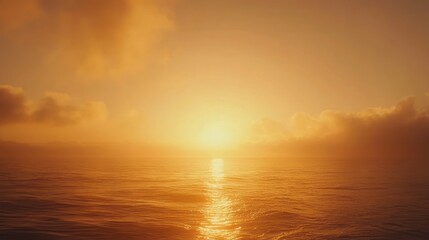 Fototapeta premium Golden sunrise over calm ocean; hazy sky, sun reflecting on water.