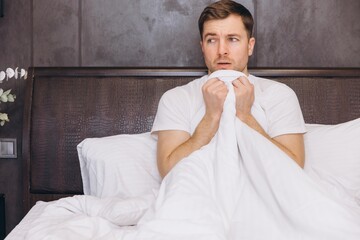 Scared Man Hiding Under Blanket in Bed Waking Up From Nightmare
