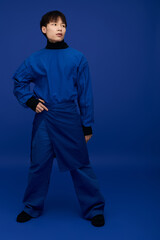 Stylish young man in blue outfit striking a confident pose against a vibrant backdrop