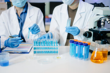 scientists in lab coats conducting research, handling glassware, and working with chemicals