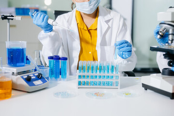 scientists in lab coats conducting research, handling glassware, and working with chemicals
