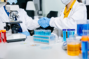 scientists in lab coats conducting research, handling glassware, and working with chemicals