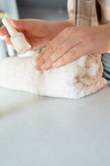 A woman gently pushes back the cuticle, preparing to apply treatment polish to strengthen brittle nails.