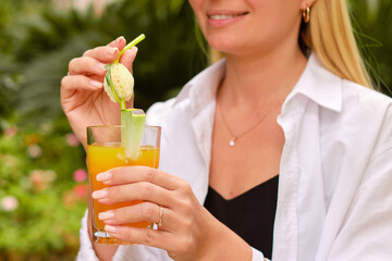 Young woman relaxing outdoors with fresh beverage surrounded by greenery emphasizing serene vacation moments and vibrant tropical ambiance